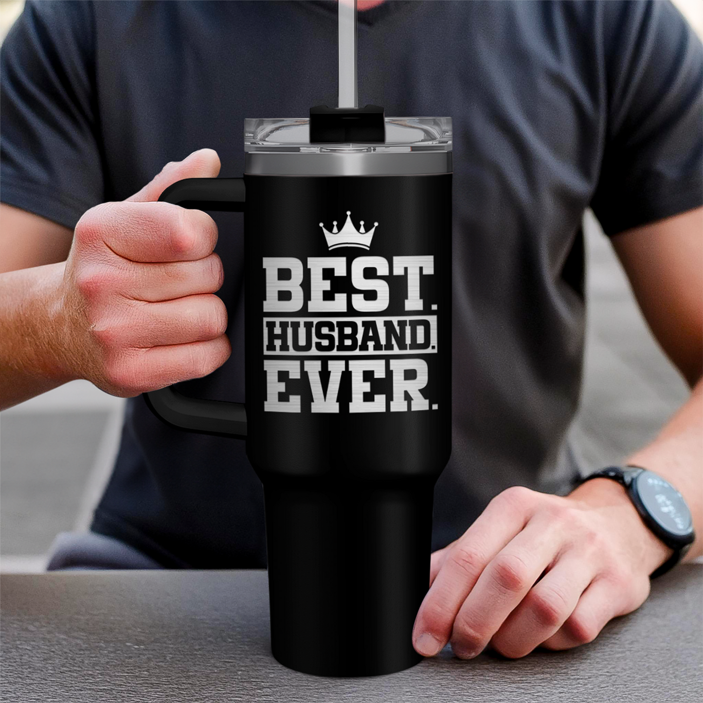 Black 40oz tumbler with handle and lid, held in hand with slogan design