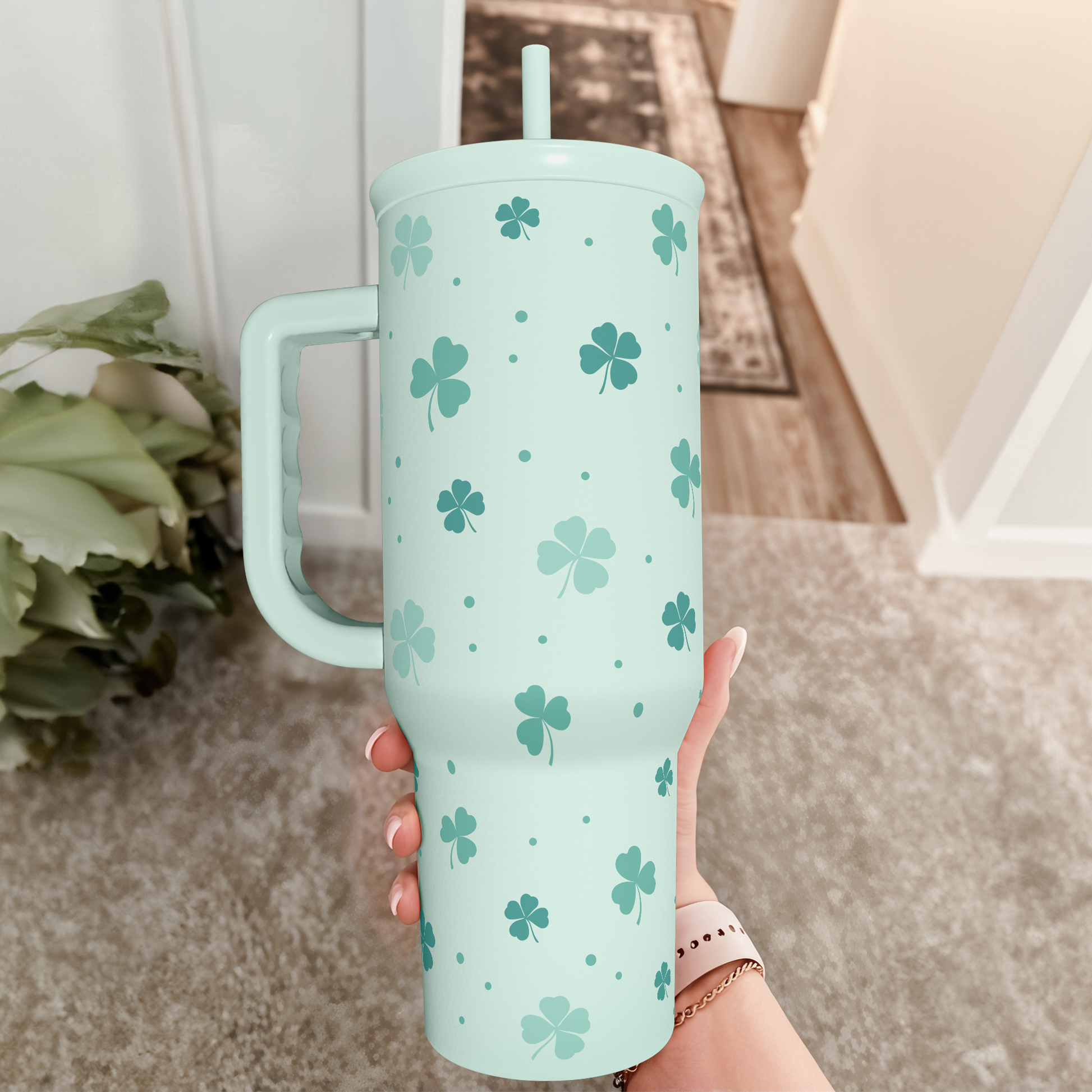 Mint green 40oz slide tumbler with handle, shamrock clover pattern, held upright indoors