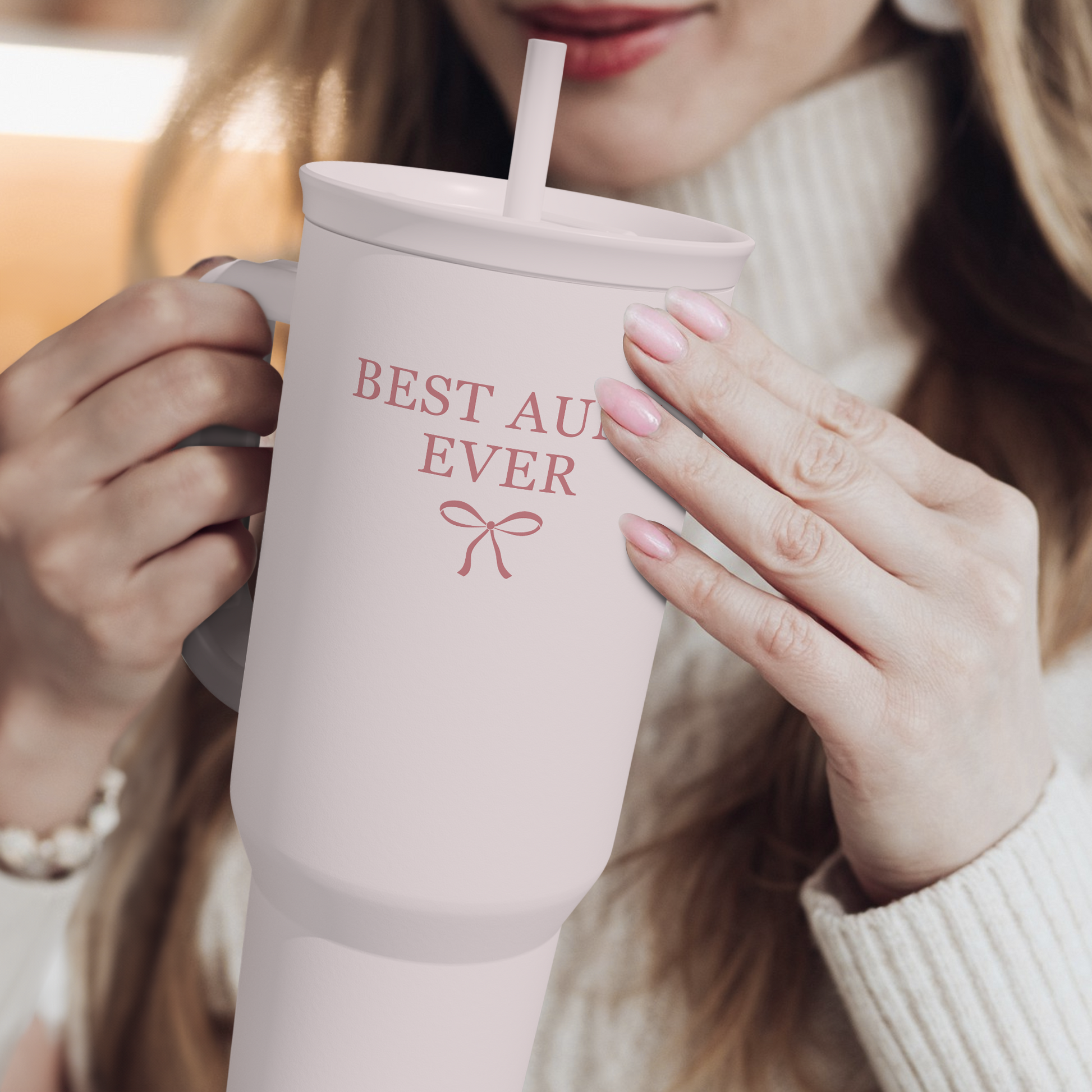 Pink 40oz tumbler with handle and straw, “Best Aunt Ever” text; being held
